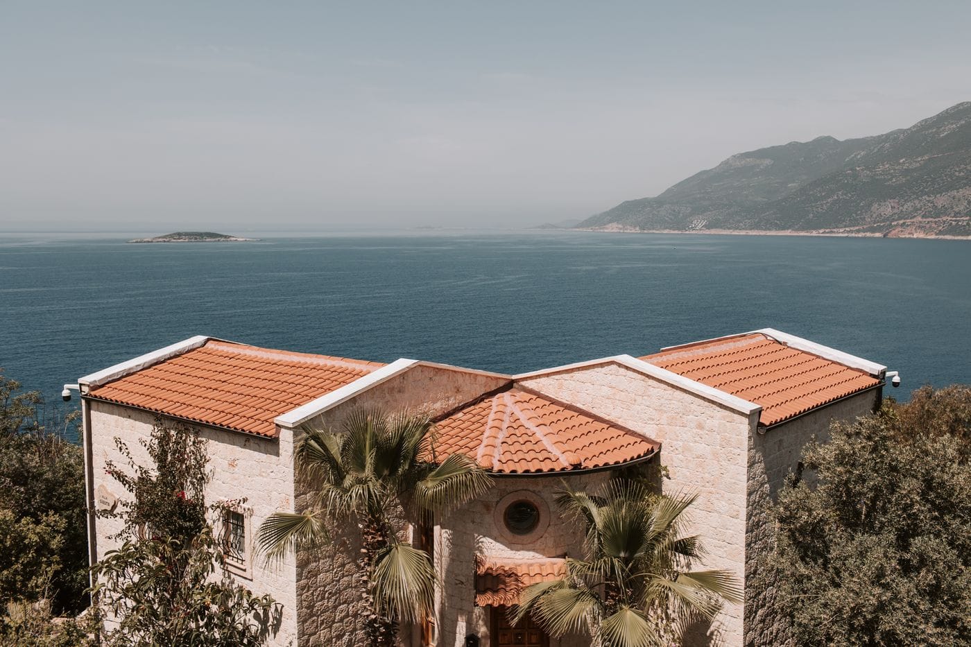 Deniz manzaralı yamaçta taş cepheli, kiremit çatılı villalar — taş ev ve taş villa yapımı