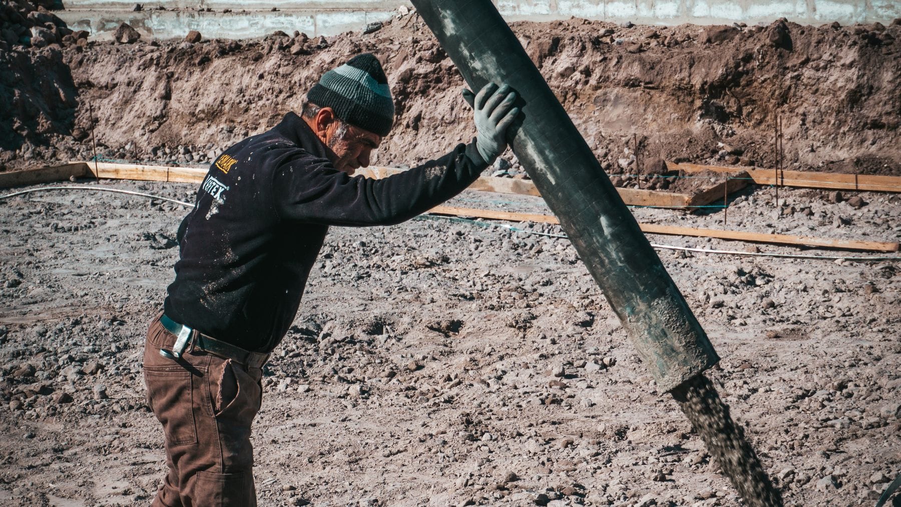 Temel kazisinda beton pompasi hortumundan akan taze beton