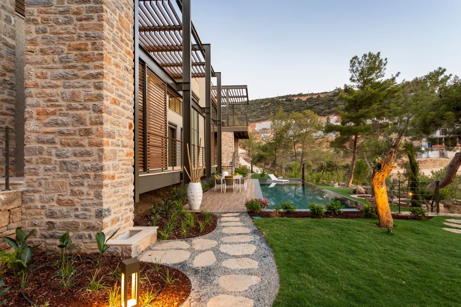 Taş cepheli modern villa ve bahçesindeki yüzme havuzu
